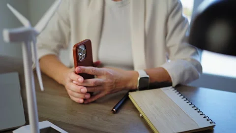 Renewable energy engineer using a smartphone at an office desk beside a win.. Stock Footage 346305469