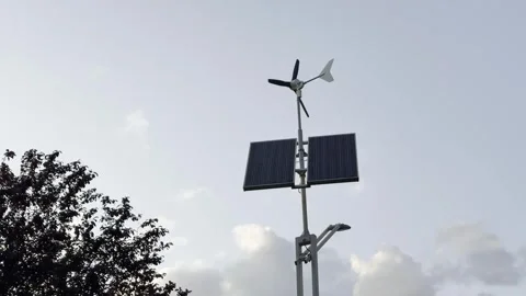 Renewable energy setup with solar panels and wind turbine against a cloudy sky Stock Footage 314456590