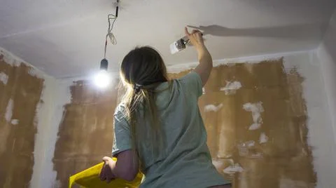 Renovation of the room, the girl performs painting work Stock Photos