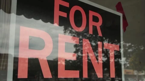 For rent sign inside window with reflection on window of trees and cars passing Stock Footage 247143484