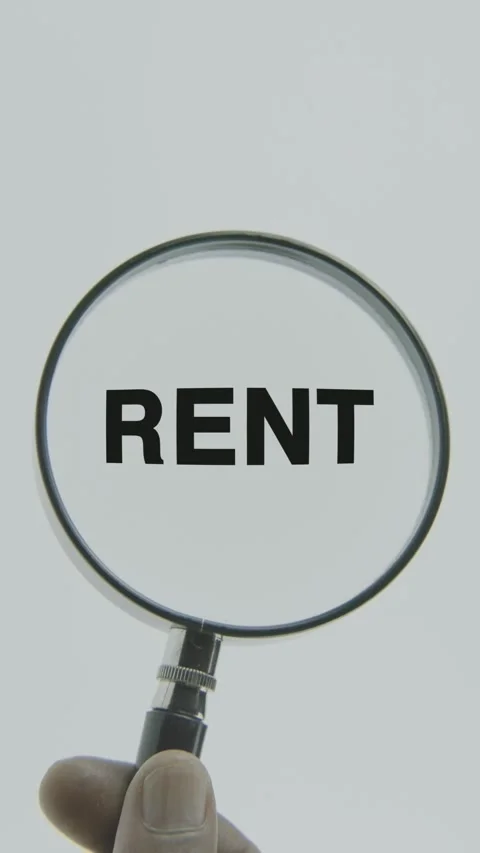 Rent text or word highlighted by a magnifying glass in a hand on a white Stock Footage 303510458