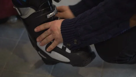 A rental worker helps put on a ski boot to a skier. Hands close-up Video stock 123922020
