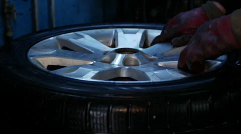 Repair and change of tires, man puts on tyre on car wheel with a special tool Stock Footage 48597176