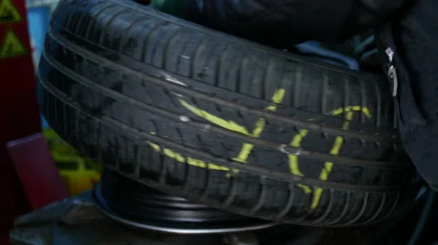 Repair and change of tires, man puts on tyre on car wheel with a special tool Stock Footage 48597511