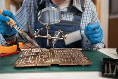 Repair of computers or electronics by a foreman in a workshop. Manual solde.. Stock Photos
