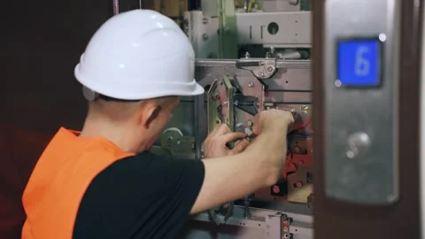 A repair engineer is fixing the elevator, the doors are open. A repairman uses a Stock Footage 266229483