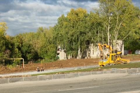 Repair or construction of roads using excavators. Autumn sky in the background. Stock Photos