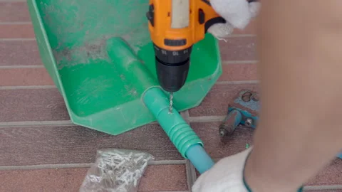 Repair the plastic dustpan with using a cordless drill hole a plastic PVC pipe. Stock Footage 326844975