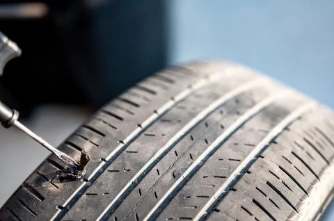 Repair plug being inserted to patch a nail tire puncture Stock Photos