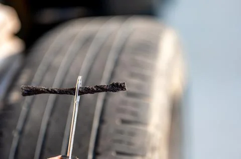 Repair plug being inserted to patch a nail tire puncture Stock Photos