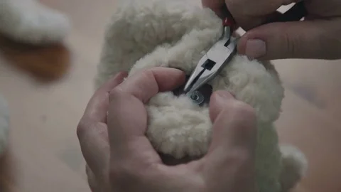 Repair of plush toys: women's hands sew a teddy bear Stock Footage