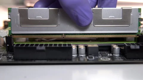 The repair technician inserts a RAM stick into the socket on the motherboard Stock Footage 151903401