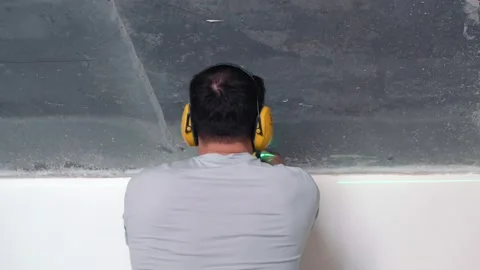 A repair worker uses a laser level to adjust the laser beam along a concrete Stock Footage 154770002