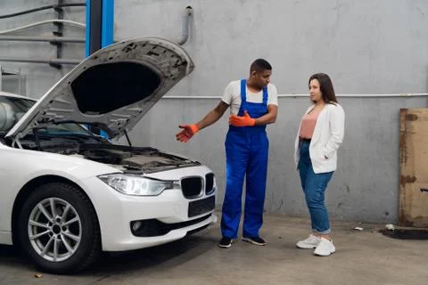 A repairer shows the client the engine of a car Stock Photos