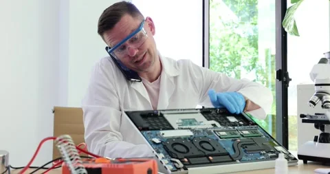 Repairing and testing computer equipment and male engineer talking on phone with Stock Footage 263170169