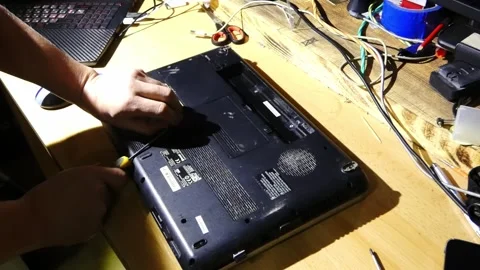 Repairing a laptop at a workbench with tools and parts in the late evening hours Video stock 328416681