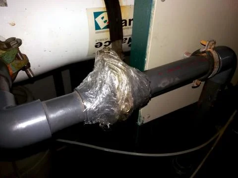 Repairing a Leaking Pipe Using Tape in a Basement Setting During Evening Hour Stock Photos