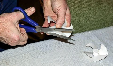 Repairing refrigerator fan using scissors for effective maintenance at home Stock Photos