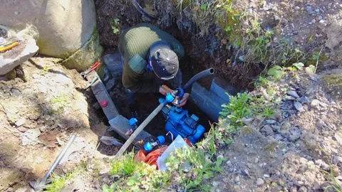 Repairing a water pump in a deep hole at a rural site in sunny weather Video stock 337440980