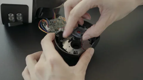 Repairing a wireless CCTV using a magnifying glass to examine the camera lens 動画素材 332696060