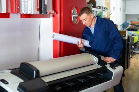 Repairman changes paper roll in plotter Fotos de archivo