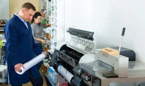 Repairman changes paper roll in plotter Stock Photos