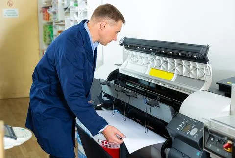 Repairman changes paper roll in plotter Stock Photos