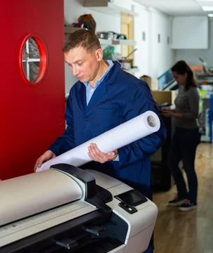 Repairman changes paper roll in plotter Stock Photos