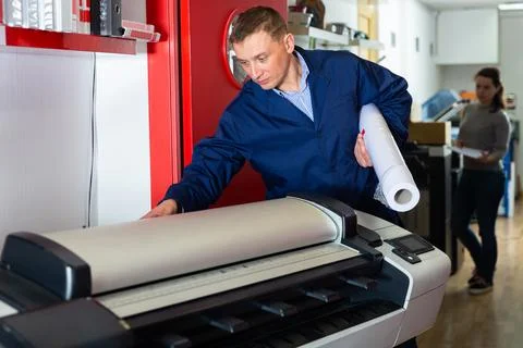 Repairman changes paper roll in plotter Foto stock