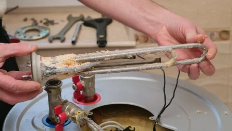 Repairman demonstrates a boiler heating element covered with limescale Stock Footage 295476879