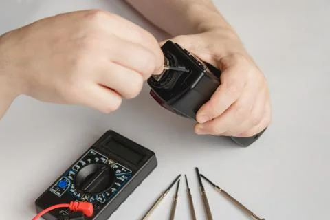 Repairman disassembling flash with screwdriver. Technician fixing broken Stock Photos