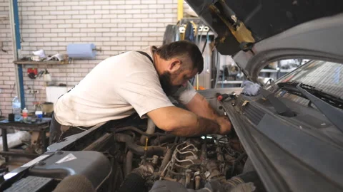 Repairman fixing engine of car using wrench at workshop or service Video stock 328639203