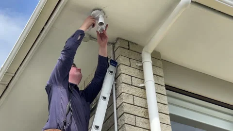 Repairman installing a double LED light on the corner of a 1980's house Stock Footage 285475750