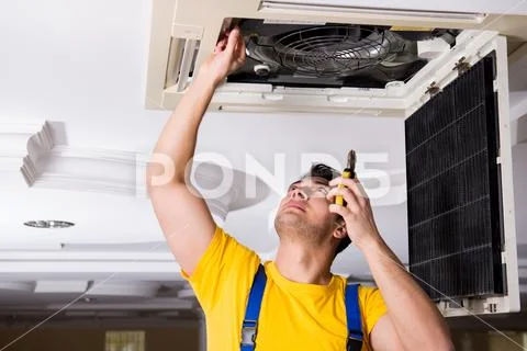 Repairman repairing ceiling air conditioning unit Stock Photos