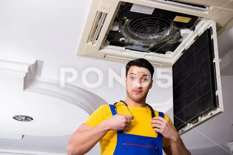 Repairman repairing ceiling air conditioning unit Stock Photos