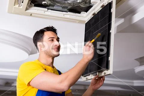 Repairman repairing ceiling air conditioning unit Stock Photos