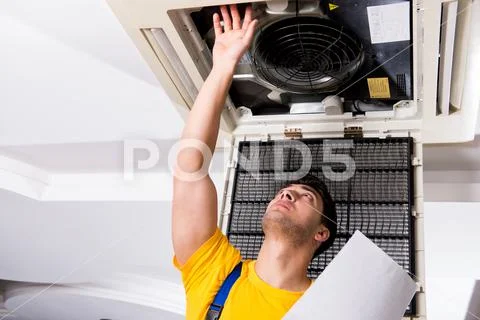 Repairman repairing ceiling air conditioning unit Stock Photos
