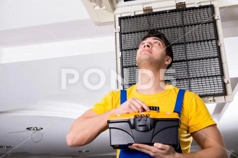 Repairman repairing ceiling air conditioning unit Stock Photos