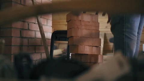 A repairman takes a block of red bricks and then stands up on a chair to start Stock Footage 90096875