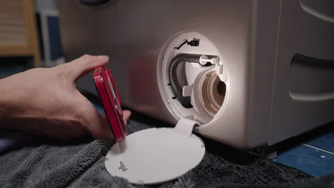 Repairman using flashlight of smartphone to illuminate inside of washing machine Stock Footage 313824066