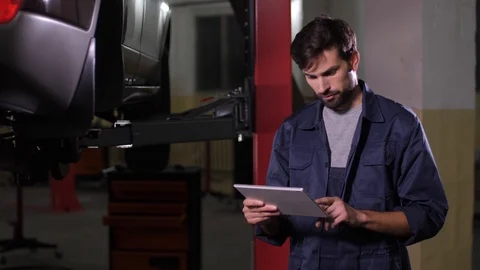Repairman working on tablet in car workshop Stock Footage 123508340