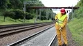 Repairman in yellow uniform with shovel in hands near railway line HD Footage