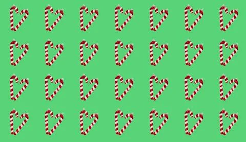 Repeated pattern of heart-shaped candy canes on a vibrant green background. Foto stock