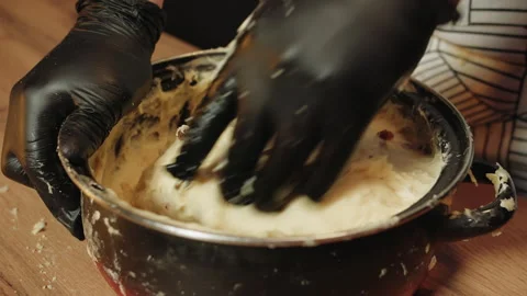 Repeatedly mixing dough using gloves in rustic kitchen setting Video stock 330536844