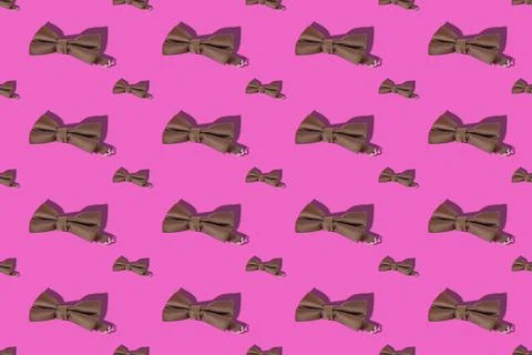 Repeating brown bow tie on pink background. Male clothing accessory. Stock Photos
