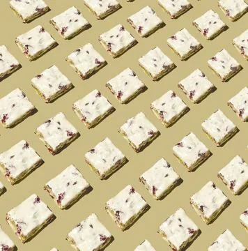 Repeating diagonal pattern of nougat cubes with nuts on beige background Stock Photos