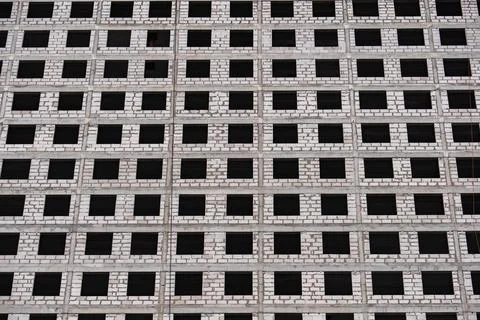 Repeating grid of empty windows framing the unfinished concrete walls of a Stock Photos