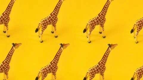 Repeating pattern of toy giraffes on a bright yellow background Stock Photos
