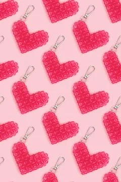 Repetitive pattern made from beaded heart keychains on a pink background. Stock Photos