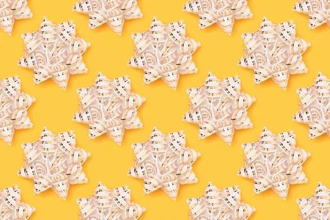 Repetitive pattern made of gold colored ribbon bows. Stock Photos